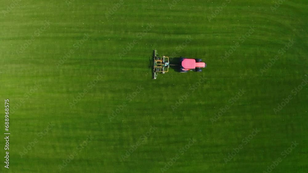 Red Tractor Cut Grass on Green Field (Slow motion) - Aerial Top Shot View. Red Tractor Cut Grass on Green Field (Slow motion) - Aerial Top Shot View.