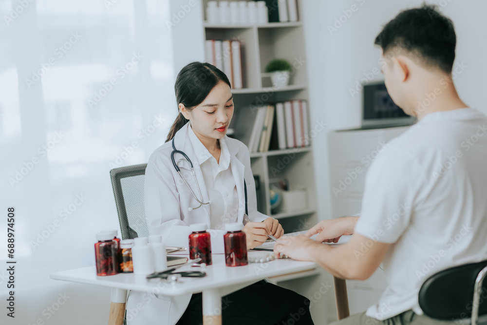 Asian female doctor discussing medicine bottle with male patient in hospital Asian female doctor discussing medicine bottle with male patient in hospital
