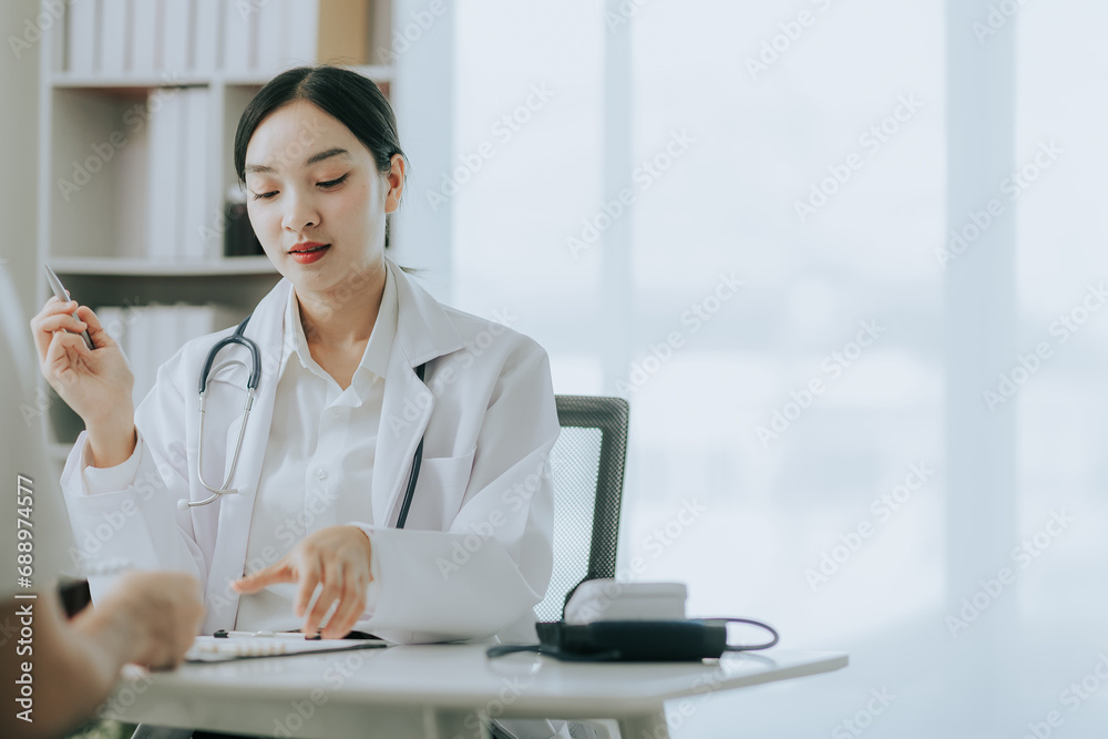 Asian female doctor discussing medicine bottle with male patient in hospital Asian female doctor discussing medicine bottle with male patient in hospital