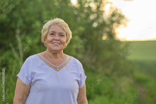 The gentle smile of a mature woman outdoors at sunset. Highlights the growing focus on nature's role in enhancing quality of life for the aged.