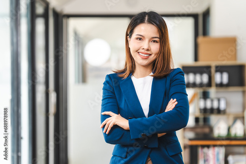 Looking camera, Happy attractive middle aged Asian people advertising manager business woman in formal suit smiles while using laptop, tablet, mobile phone, with laptop and coffee on desk.