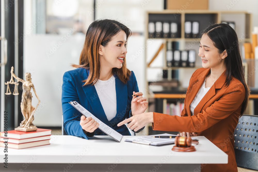 Two young and middle-aged Asian women lawyers in formal suits discuss legal contract, focusing on legislation and women's rights in law office. Two young and middle-aged Asian women lawyers in formal suits discuss legal contract, focusing on legislation and women's rights in law office.