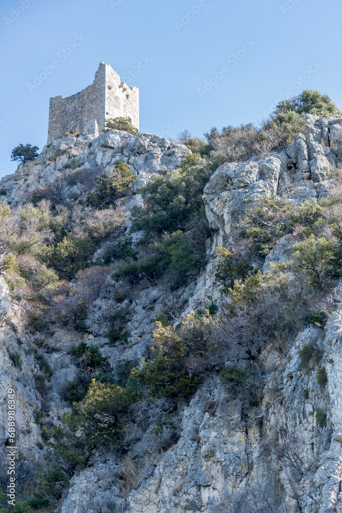 Castelmarino tower ruin looms out of steep rocky hill at bog on shore, near Marina di Alberese, Italy