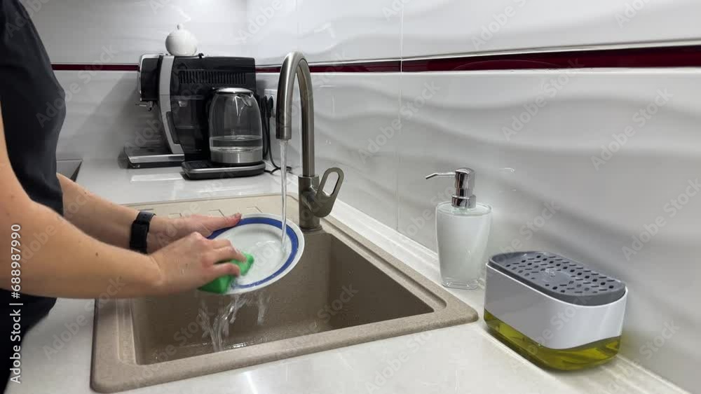 Woman washing plate by hands under running water in sink at modern kitchen, washing dishes, slow motion video Woman washing plate by hands under running water in sink at modern kitchen, washing dishes, slow motion video