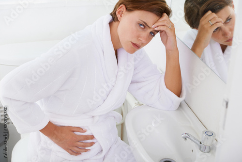 Nausea, pregnant woman and morning sickness in bathroom, unhappy and hand on stomach. Mirror reflection, moody and frustrated with illness, pregnancy and struggling with migraine pain on sink