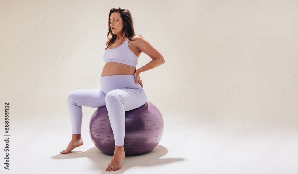Pregnant woman practicing prenatal yoga on exercise ball for maternal health and wellness Pregnant woman practicing prenatal yoga on exercise ball for maternal health and wellness