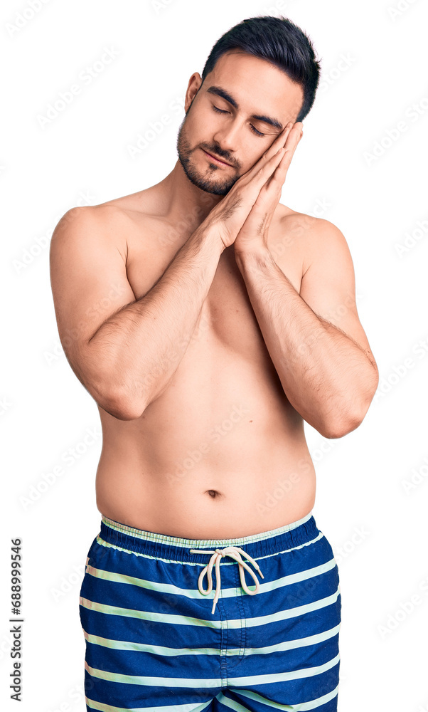 Fototapeta premium Young handsome man wearing swimwear sleeping tired dreaming and posing with hands together while smiling with closed eyes.