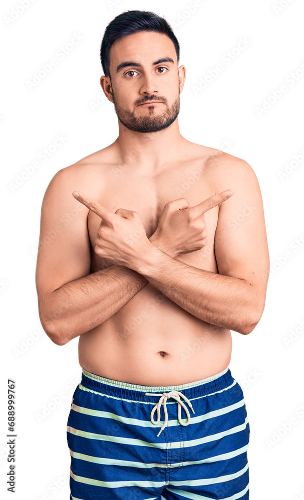 Fototapeta premium Young handsome man wearing swimwear pointing to both sides with fingers, different direction disagree