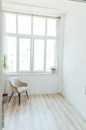 Bright room with a large window and an armchair with a room flower Interior