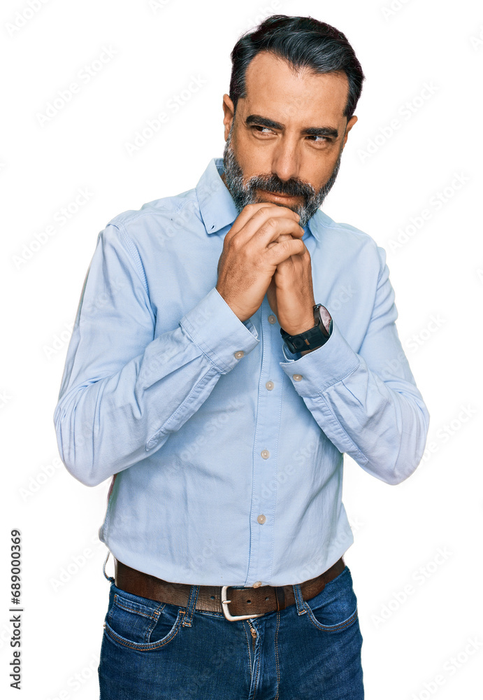 Middle aged man with beard wearing business shirt laughing nervous and excited with hands on chin looking to the side Middle aged man with beard wearing business shirt laughing nervous and excited with hands on chin looking to the side