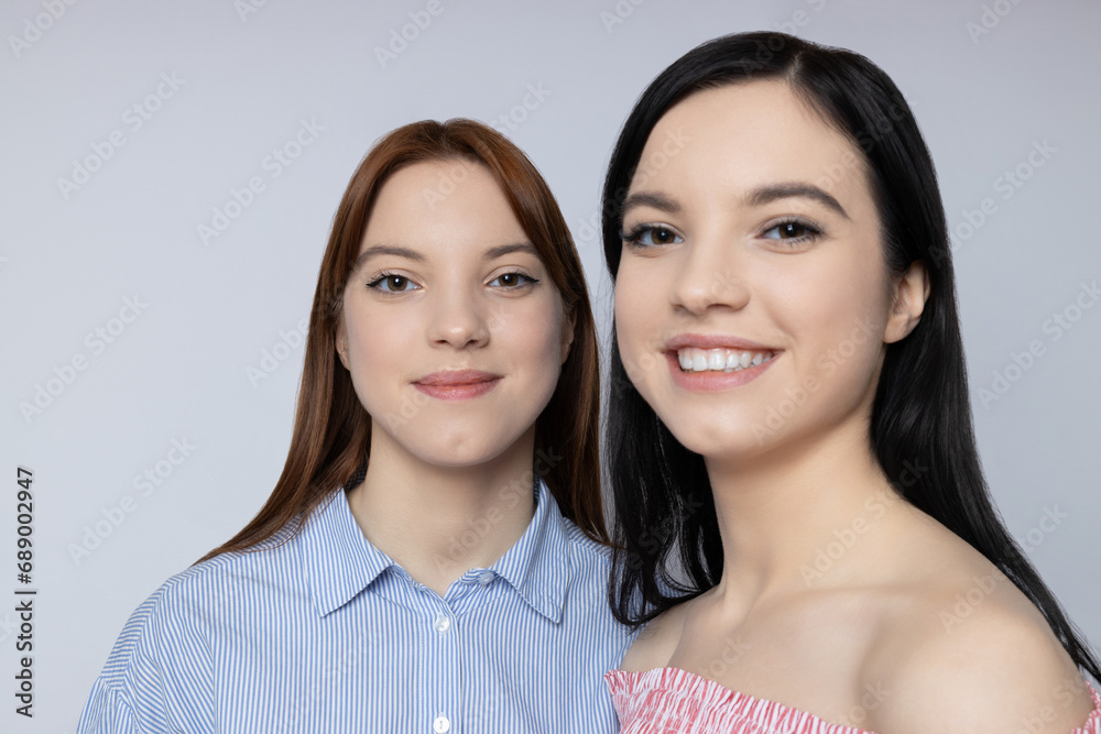 Two sisters pose on a light background