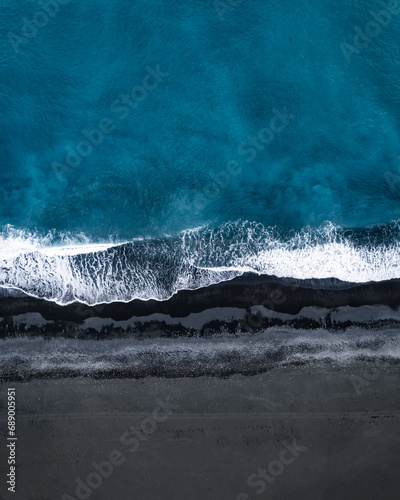aeriel view of ocean waves on black sand beach