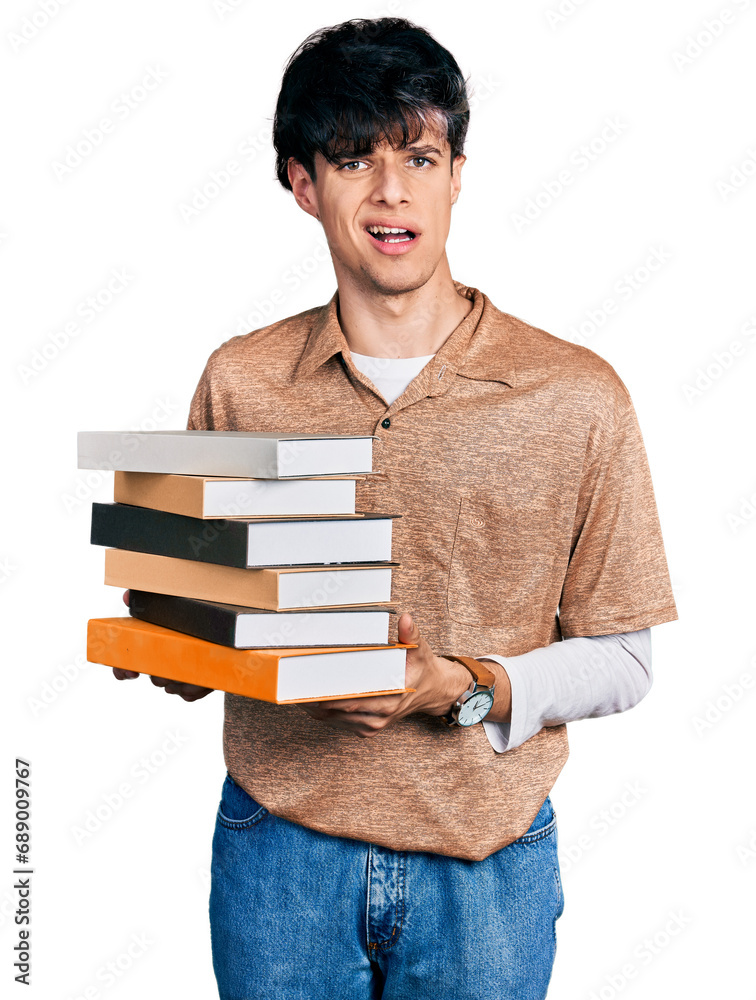Handsome hipster young man holding a pile of books clueless and confused expression. doubt concept. Handsome hipster young man holding a pile of books clueless and confused expression. doubt concept.