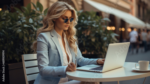 Social media manager woman working with laptop in center of city, Elegant outfit blue and white. photo