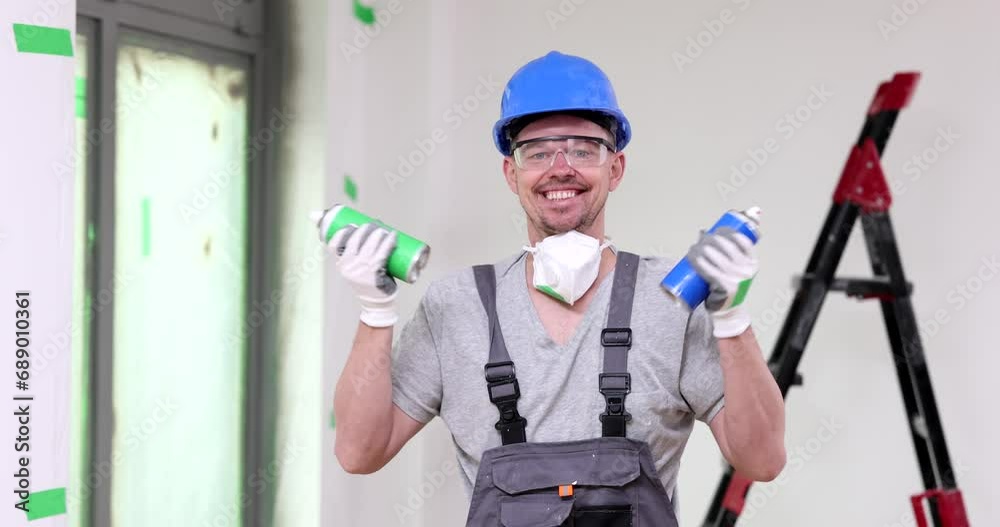 A happy builder shakes a spray with paint, a close-up. Equipment for repairing an apartment A happy builder shakes a spray with paint, a close-up. Equipment for repairing an apartment
