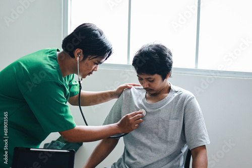 Asian male doctor using a stethoscope listen to the heartbeat of the patient sitting in clinic photo