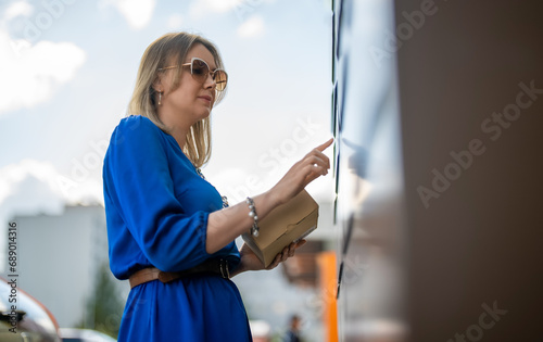 Woman sending mail via automated self-service post terminal machine. photo