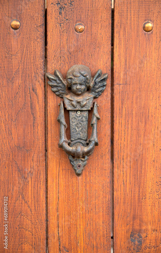 Old knocker in the shape of angel on wooden door closeup