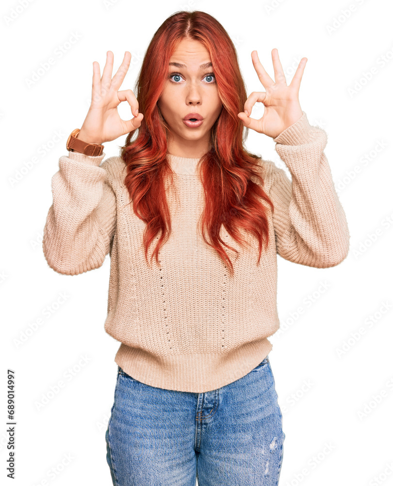 Young redhead woman wearing casual winter sweater looking surprised and shocked doing ok approval symbol with fingers. crazy expression Young redhead woman wearing casual winter sweater looking surprised and shocked doing ok approval symbol with fingers. crazy expression