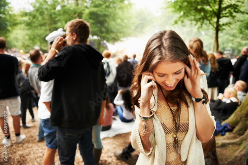 Music festival, event and woman outdoor with phone call, conversation and noise from crowd at a party. Contact, person and confused by loud, sound or listening to smartphone for communication at rave photo