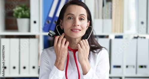 Woman doctor putting on stethoscope to auscultate patient in clinic 4k movie slow motion. Health care concept