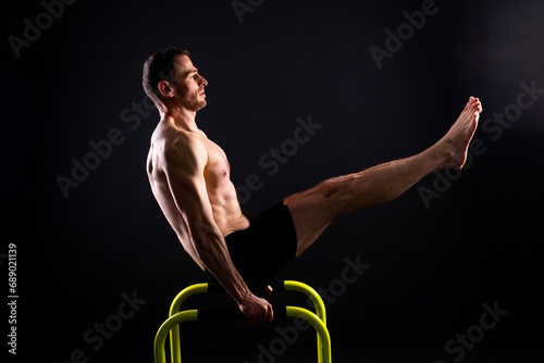 Canvas Print Male gymnast performing handstand on parallel bars, studio shot