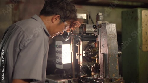 engineer checking a steel lathe machine. Male worker working in a factory. lathe machine works by rotating the workpiece around a stationary cutting tool and leaving behind a nicely shaped workpiece. photo