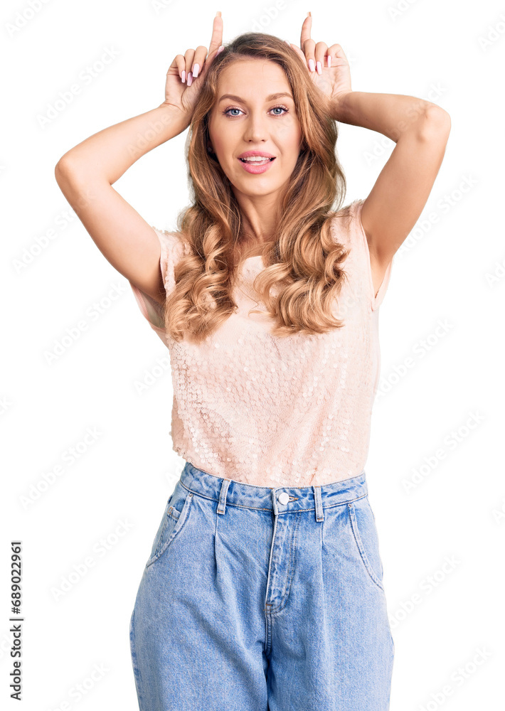 Young beautiful caucasian woman with blond hair wearing casual clothes doing funny gesture with finger over head as bull horns Young beautiful caucasian woman with blond hair wearing casual clothes doing funny gesture with finger over head as bull horns