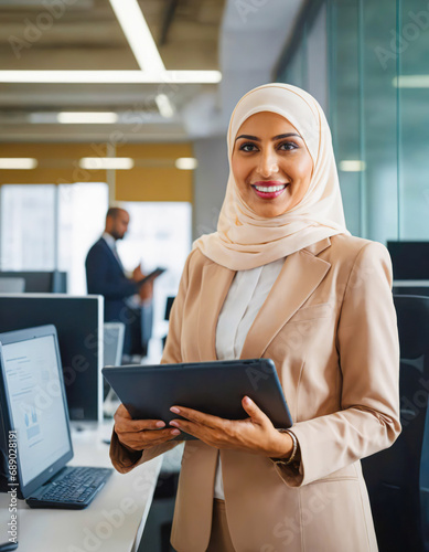 Focused muslim businesswoman in hijab working on a tablet and standing in modern office