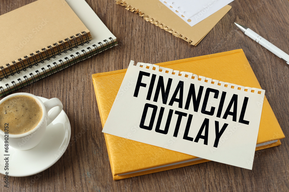 Financial Outlay. cup of coffee and yellow notepad. text on torn page Financial Outlay. cup of coffee and yellow notepad. text on torn page