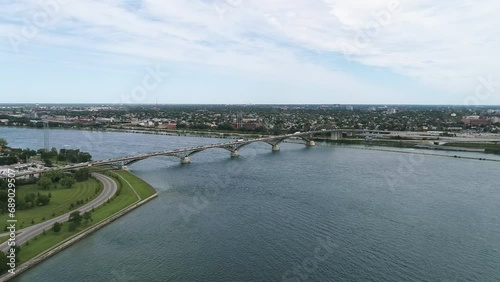 Drone captures a stable shot of the Fort Erie Peace Bridge, with cars travelling to and from Fort Erie to Buffalo. A city skyline is seen in the distance. photo