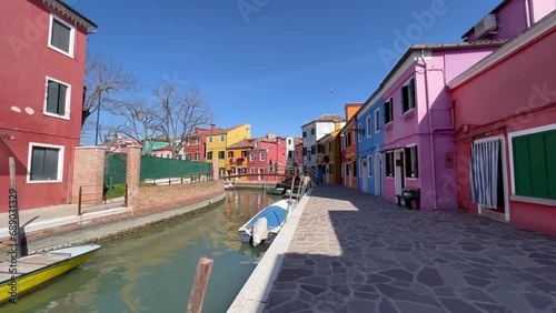 4K Gimbal Shot Unveiling Vibrant Burano Island, Venice, Italy: Colorful Houses, Tranquil Canals, Historic Ambience; Boats Drift in the Village Known for Vibrant Architecture and Cultural Heritage. photo