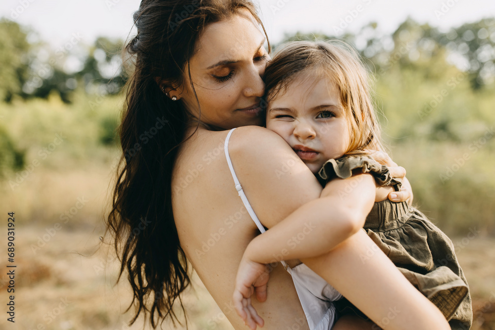 Closeup portrait of a mother holding her little daughter in arms, outdoors. Closeup portrait of a mother holding her little daughter in arms, outdoors.
