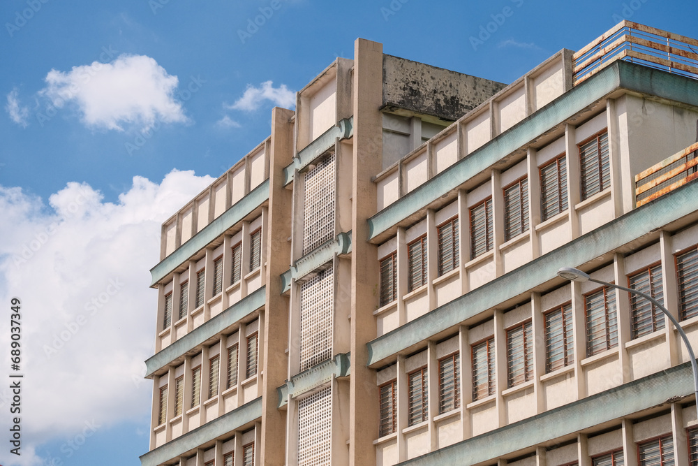 Facade of a 1960s old modernism architecture concrete building under the blue sky cloudy day in the center of Ipoh city, Perak, Malaysia.