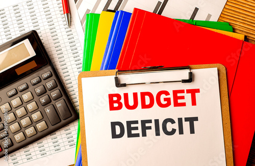 BUDGET DEFICIT text written on paper clipboard with chart and calculator