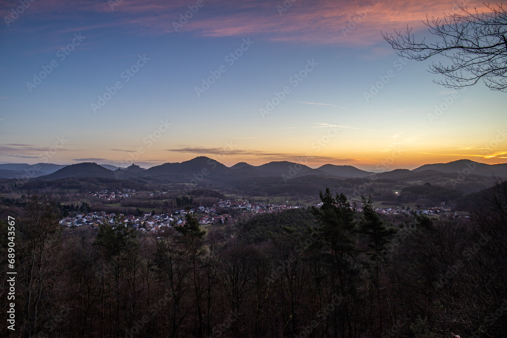 Hilly landscape shot on a sandstone rock in the forest. Cold morning mood at sunrise at a viewpoint. Winter morning in Palatinate Forest, Germany