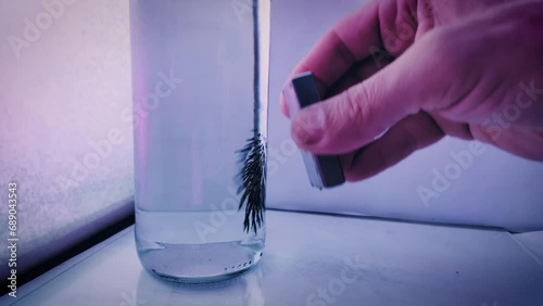 Iron filings in water being moved by a neodymium magnet. photo