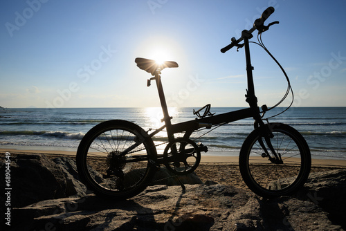 Fototapeta Naklejka Na Ścianę i Meble -  A folding bike on sunrise seaside rocks