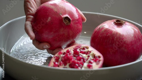 Holding cut pomegranate with bright red seeds on plate healthy anti-oxidants cardioprotective properties photo