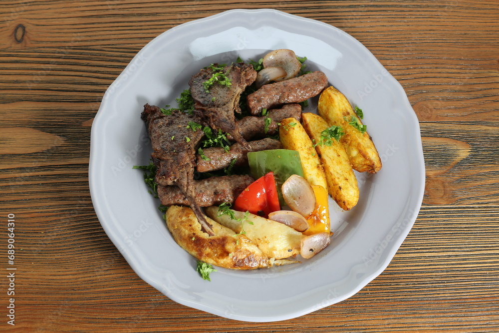 Mix kofta kabab and lamb chop with potato veggies, tomato and onion served in dish isolated on table top view of arabic food Mix kofta kabab and lamb chop with potato veggies, tomato and onion served in dish isolated on table top view of arabic food