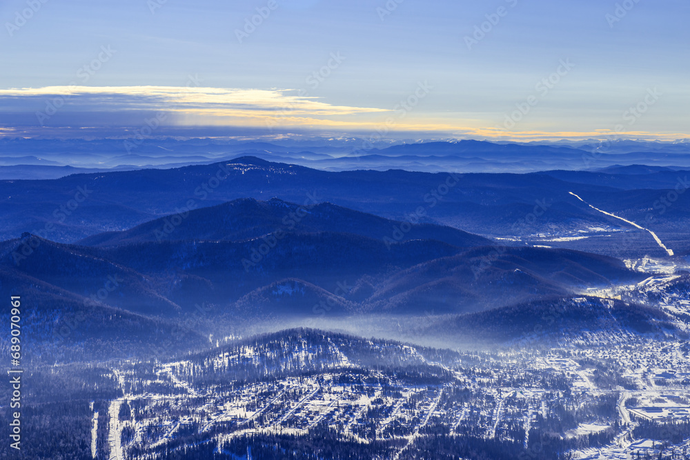 Winter nature panorama with Sheregesh ski resort in Altai, Russia, picturesque view, aerial tonal perspective, abstract background with range mountains white and blue sky, hills covered trees