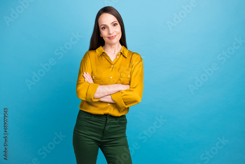 Photo of cool confident woman dressed yellow shirt arms crossed empty space isolated blue color background