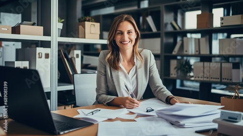 A smiling businesswoman multitasking at her desk, surrounded by paperwork and contemporary office decor