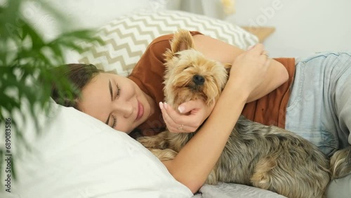 A young woman is lying on the bed and playing with her dog.