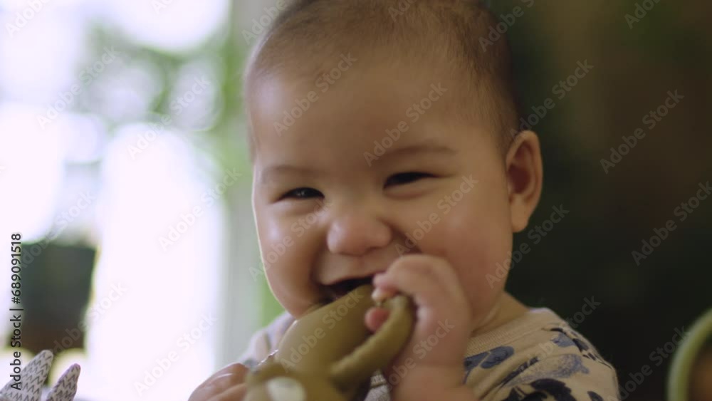 Cute mixed race Asian baby chewing teething toy and smiling laughing. Slow motion shallow depth of field Cute mixed race Asian baby chewing teething toy and smiling laughing. Slow motion shallow depth of field