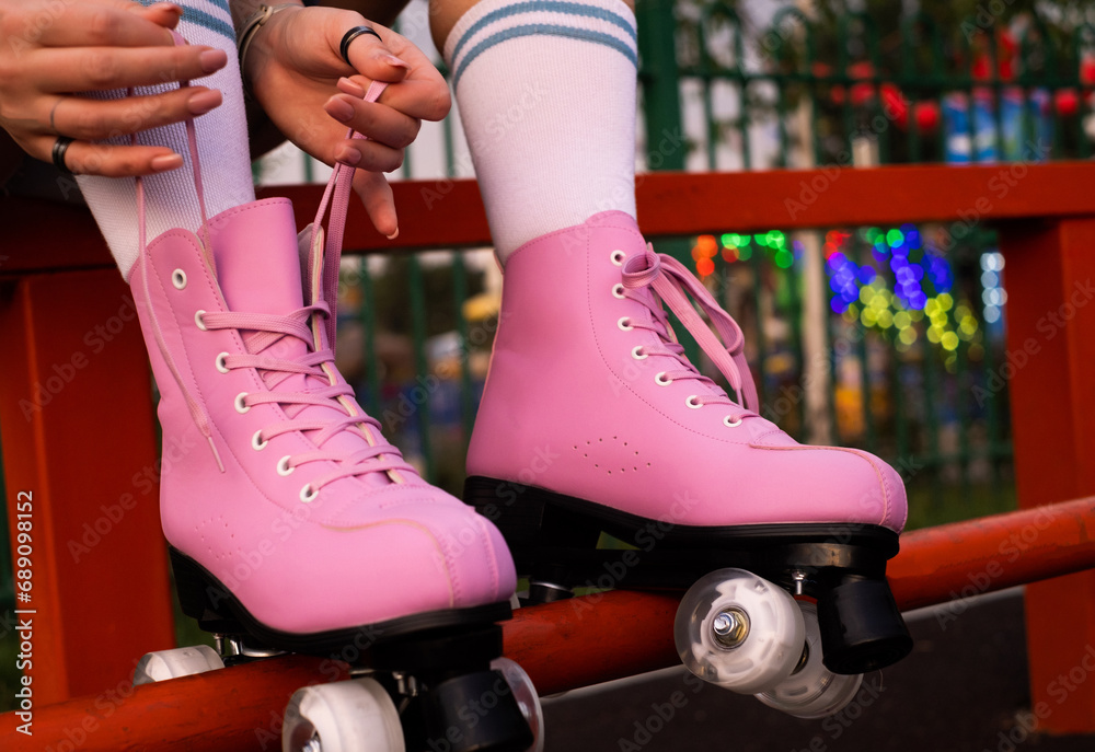 Close-up of figure skater's hands tying shoelaces on roller skates, young woman roller skating in the park close-up - obrazy, fototapety, plakaty 