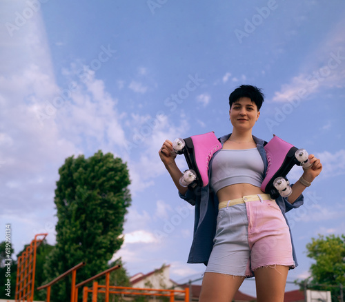 Fototapeta Naklejka Na Ścianę i Meble -  athletic woman posing with a pair of roller skates on her shoulder, smiling and looking away, sport lifestyle concept, copy space