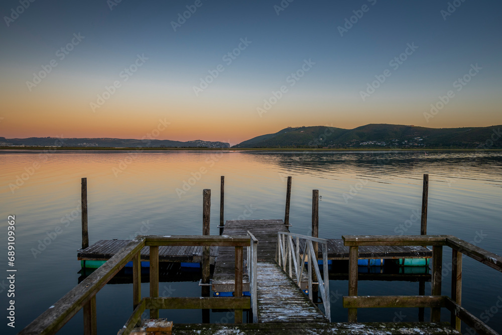 Fototapeta premium Knysna Lagoon with jetty and fishing boats at sunset in the Garden Route South Africa