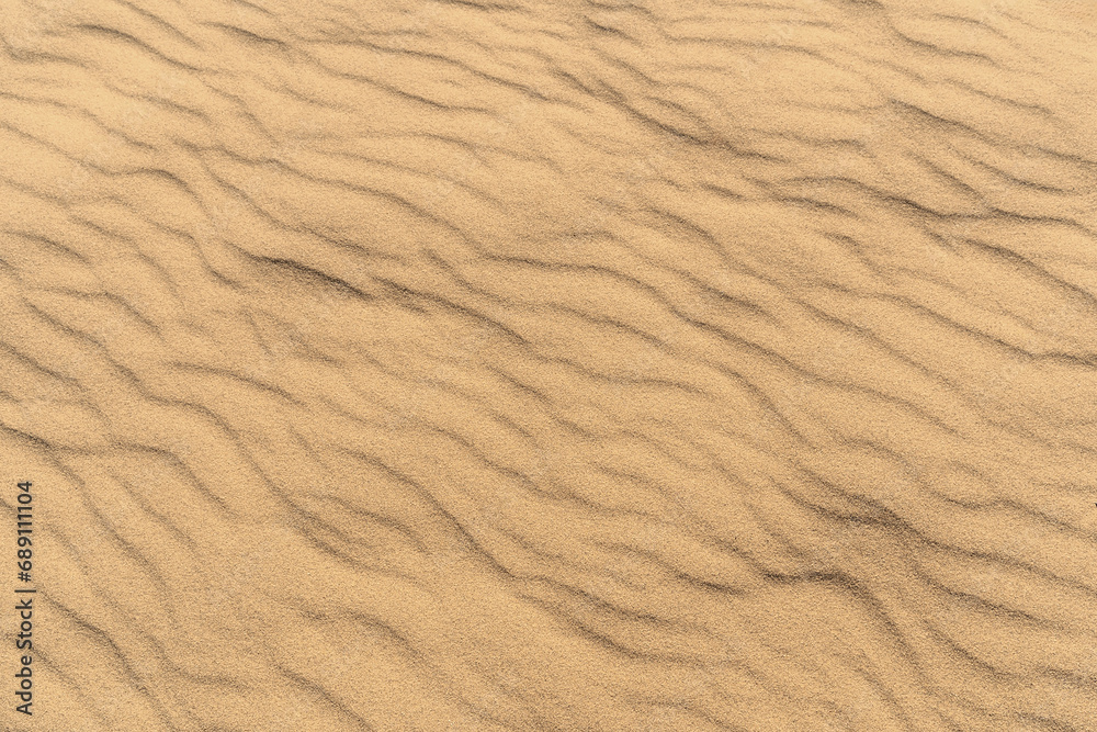 Natural background of sunlit sand, adorned with a vibrant shade of yellow. Top view, copy space. Natural background of sunlit sand, adorned with a vibrant shade of yellow. Top view, copy space.
