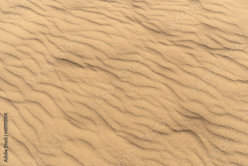 Natural background of sunlit sand, adorned with a vibrant shade of yellow. Top view, copy space.